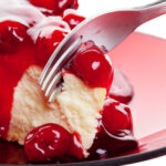 Mouth watering cherry cheesecake macro with fork.  Shot on white background.